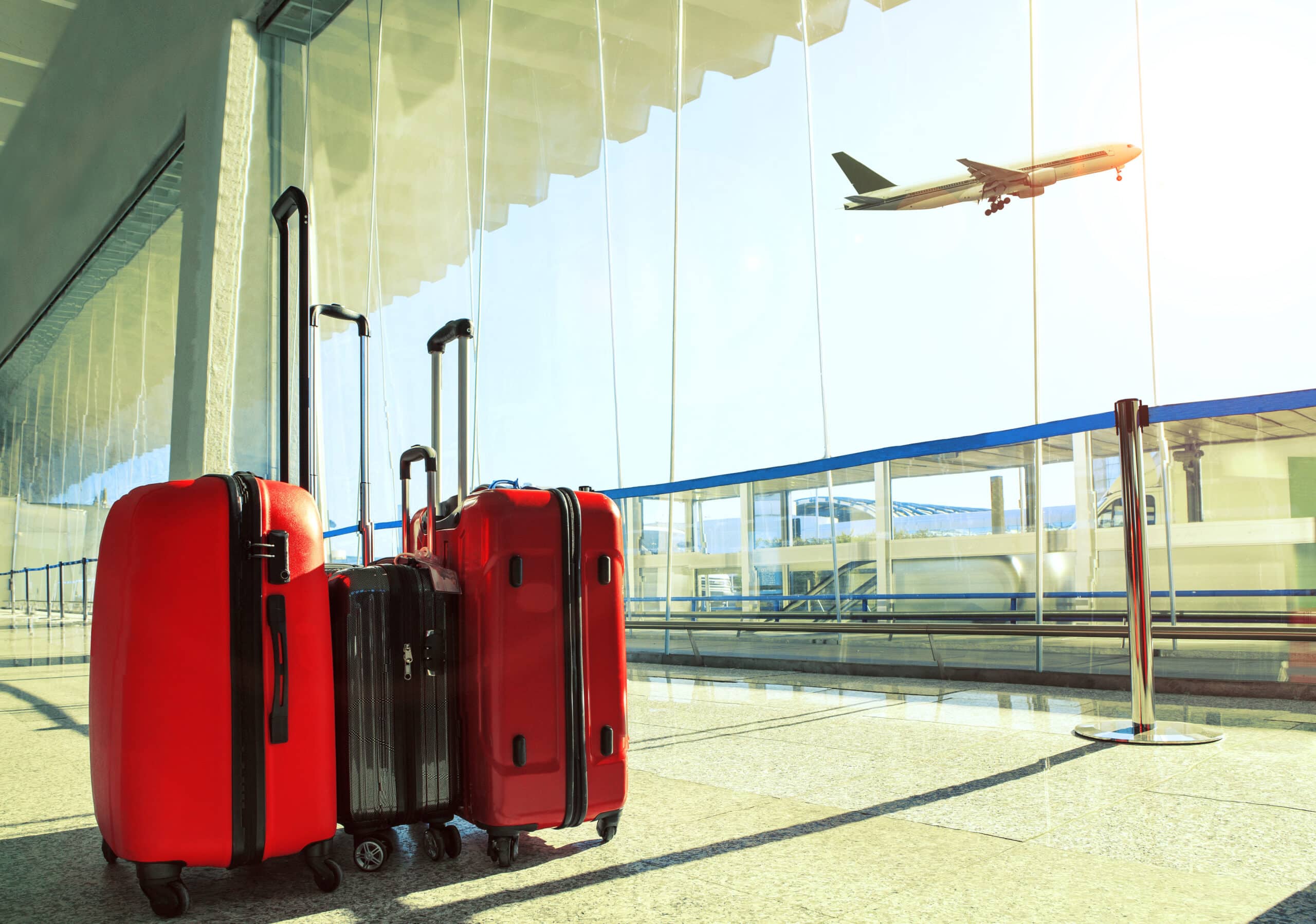 Luggage at an airport terminal with a plane taking off in the background, symbolizing travel insurance for ministry missions and events.