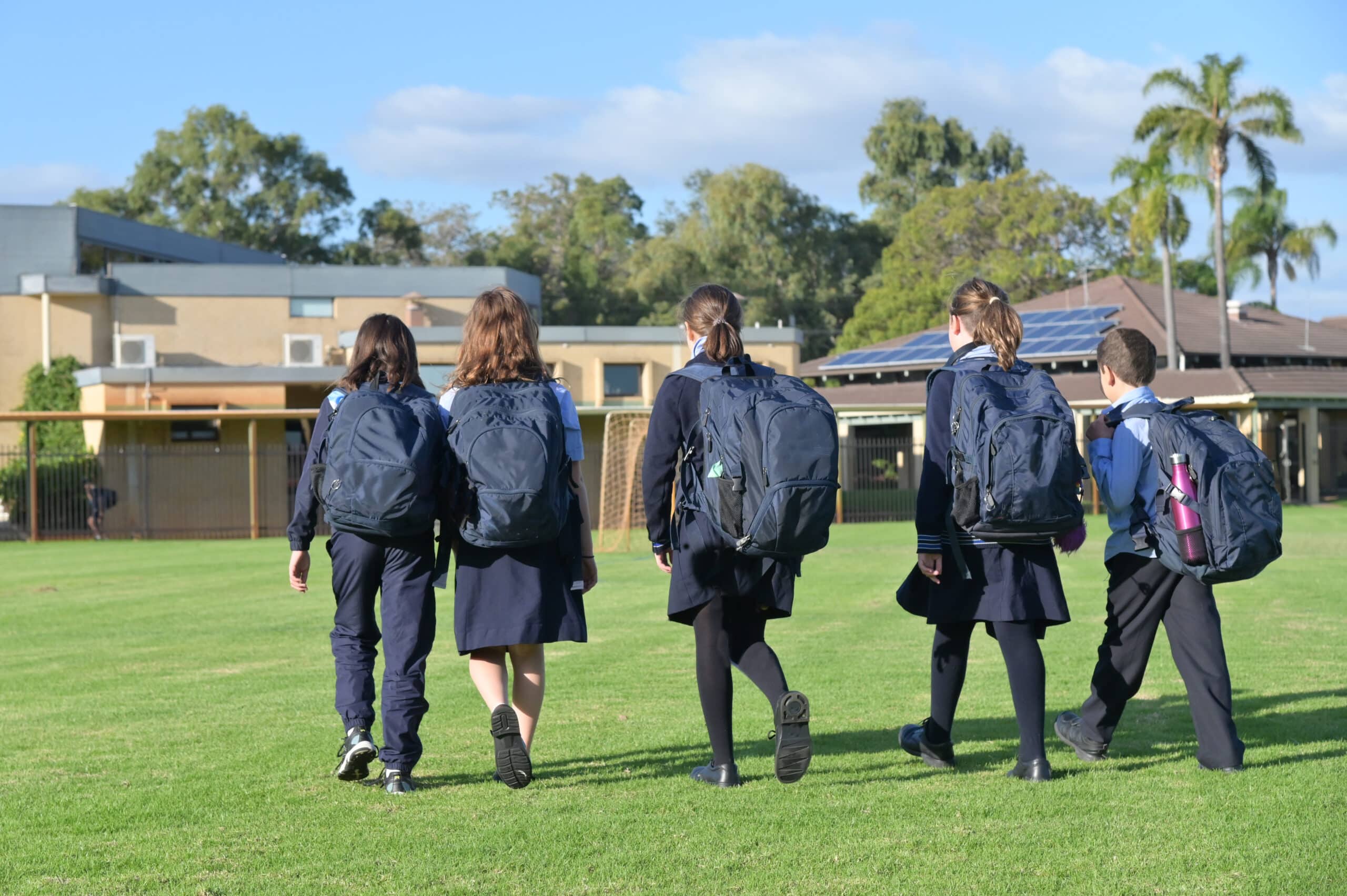 Group,Of,Australian,School,Students,Wearing,School,Uniform,Walking,Together Students walking on school grounds with backpacks, representing Christian education and community values in Australian schools.