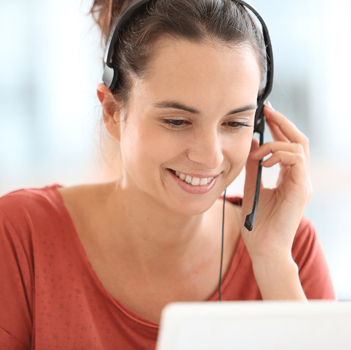 Smiling woman wearing a headset, engaged in a conversation while using a laptop, representing customer support for ACS Financial's business lending services.