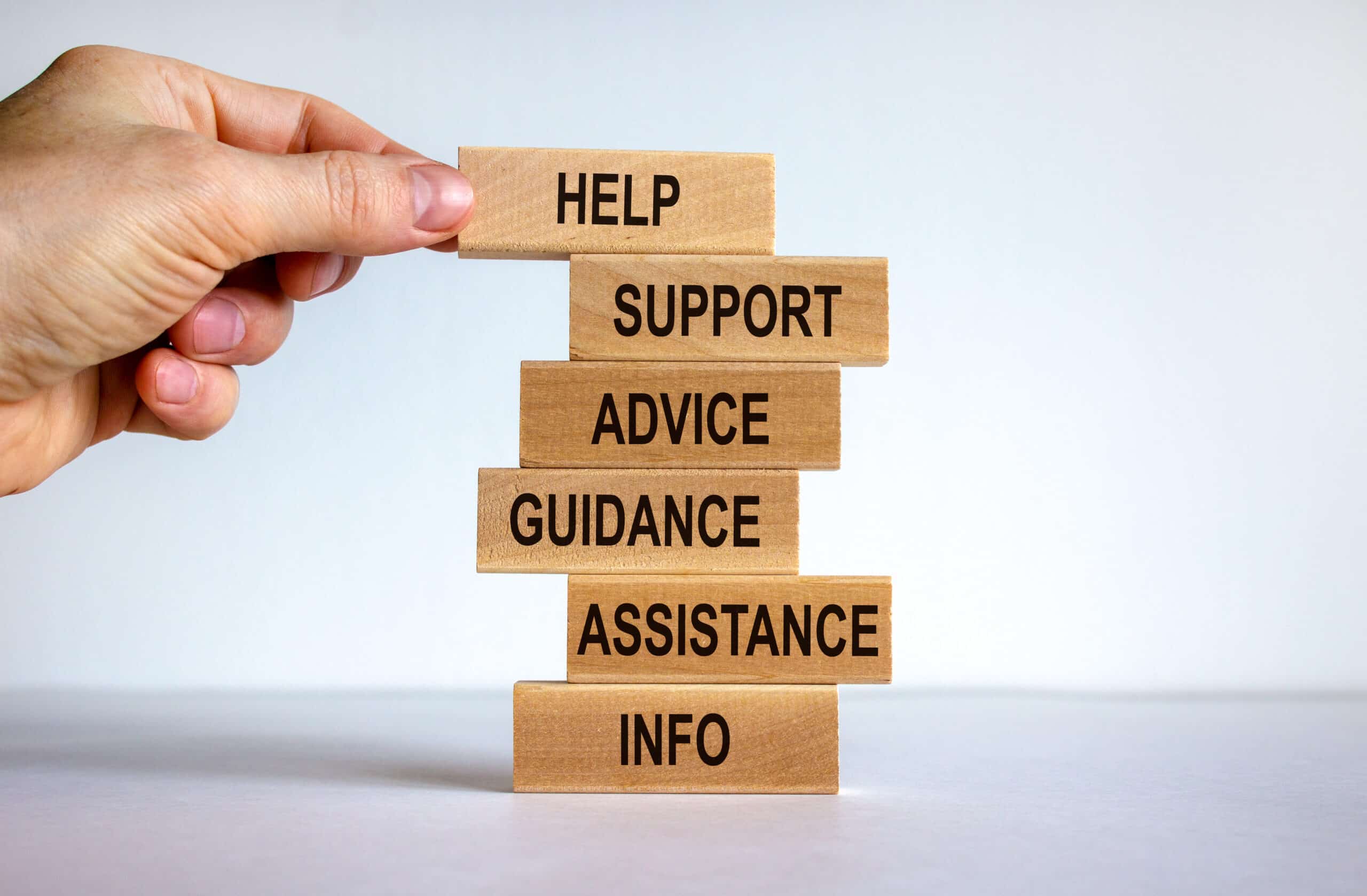 Hand holding wooden blocks with words "Help," "Support," "Advice," "Guidance," "Assistance," and "Info," symbolizing financial advisory services for Christian churches and schools.