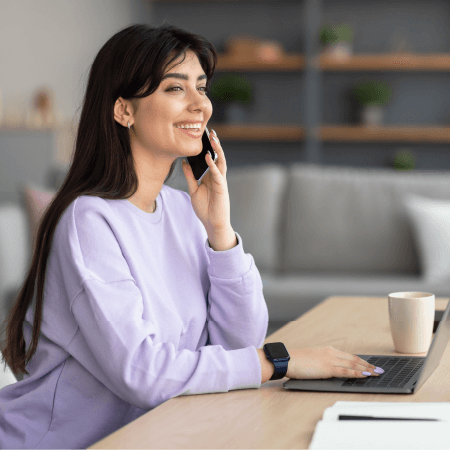 Peace of mind support worker Woman smiling on phone while using laptop, representing support and communication in aged care insurance services.
