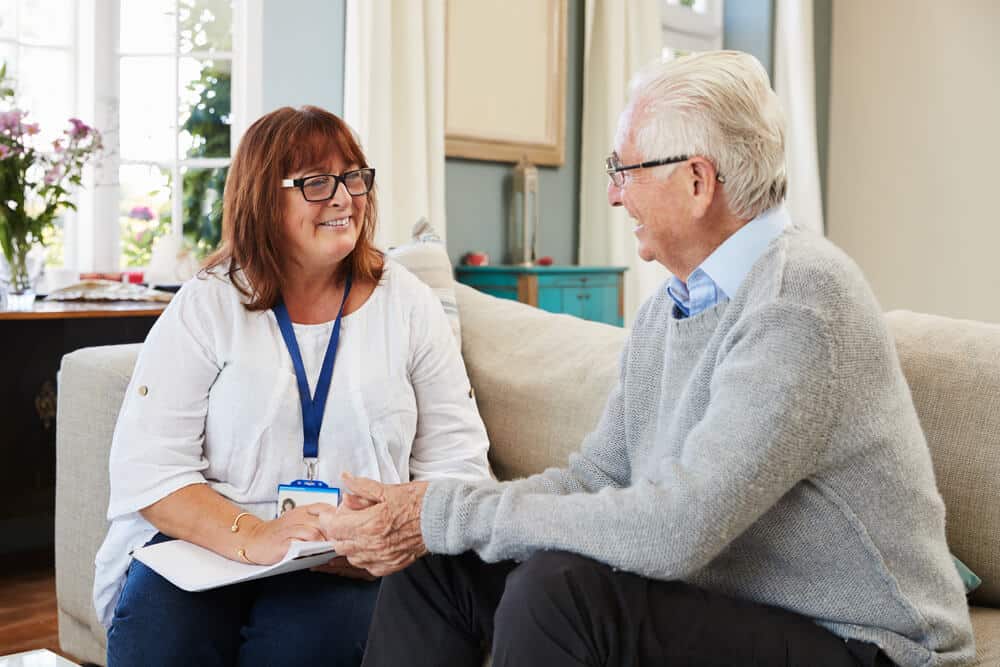 Professional Indemnity Aged care worker engaging with elderly client in a comfortable setting, highlighting professional care and communication essential for aged care services.