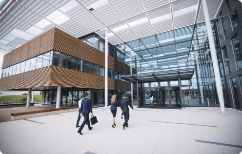 Business people walking outside a modern corporate building facility, representing commercial property loans solutions.