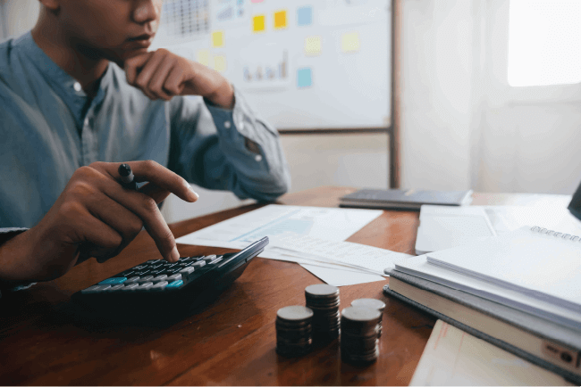 Financial officer using a calculator to evaluate insurance premium costs and prevent church underinsurance risks.