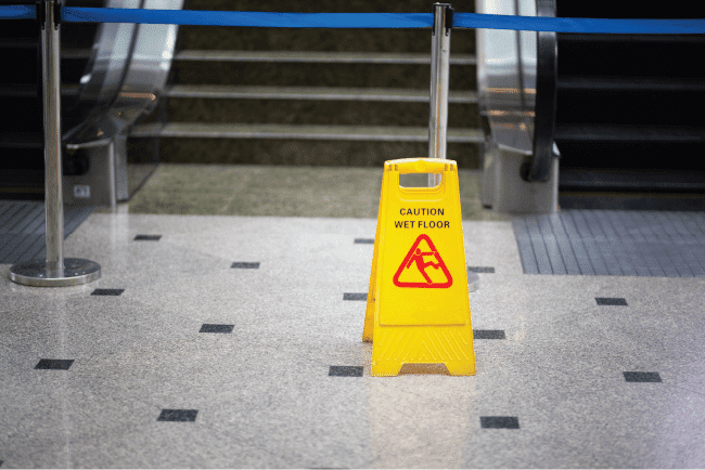 Yellow wet floor warning sign standing on a tiled surface, illustrating public liability risks for church buildings.