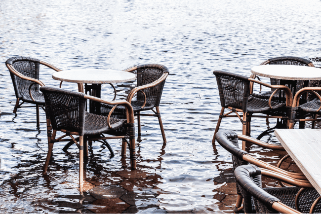 Flooded outdoor restaurant patio seating area, demonstrating property insurance underwriting disaster risks.