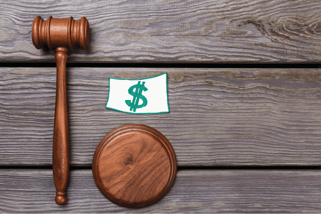 Wooden gavel and a paper dollar sign cutout placed on a rustic wood surface, illustrating church asset protection.