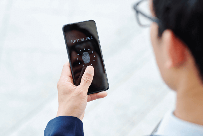 Man using a smartphone fingerprint scanner for security, highlighting ministry data breach and cyber liability protection.