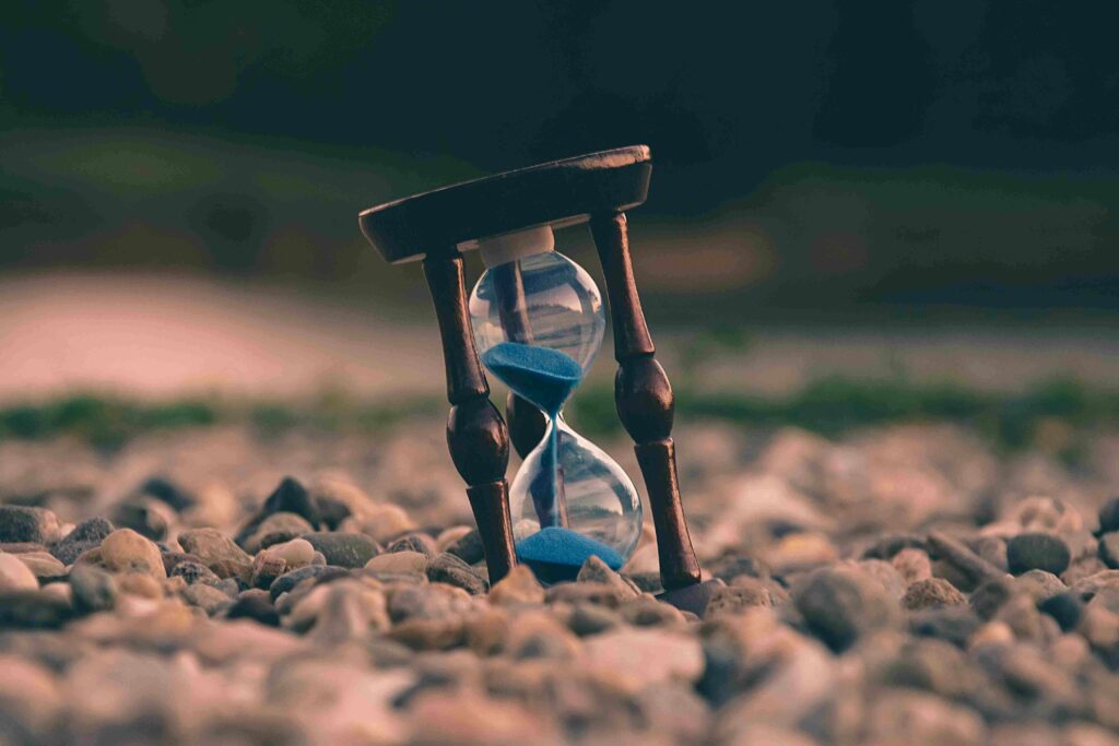 Hourglass sitting on dry rocky soil as sand falls through, illustrating trends in aged care insurance pricing.