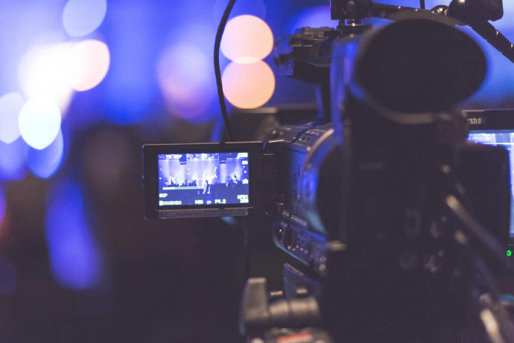 Professional video camera recording a live broadcast, highlighting media protection and public liability for church events.