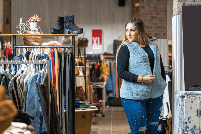 Woman browsing clothing racks inside a thrift store, highlighting risk management for running a safe church op shop.
