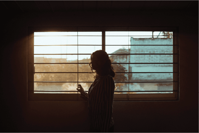 Silhouette of a woman standing at a barred window, illustrating legal liabilities and specific risks for aged care providers.