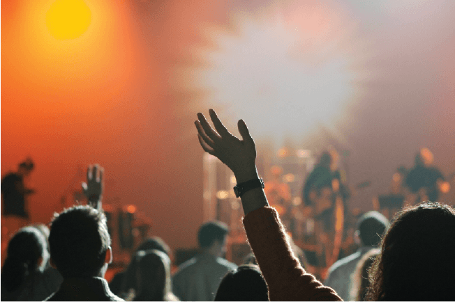Worship team concert event with crowd raising hands, representing community focused church programs and public liability.