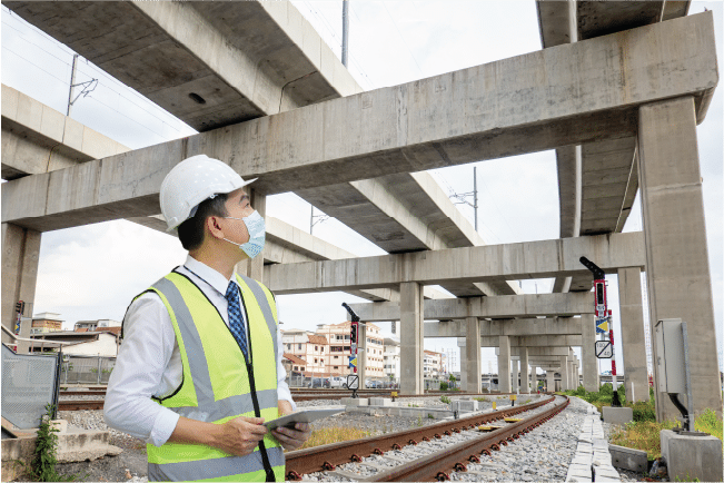 Site inspector evaluating construction infrastructure under bridge pillars for property insurance underwriting risk assessment.