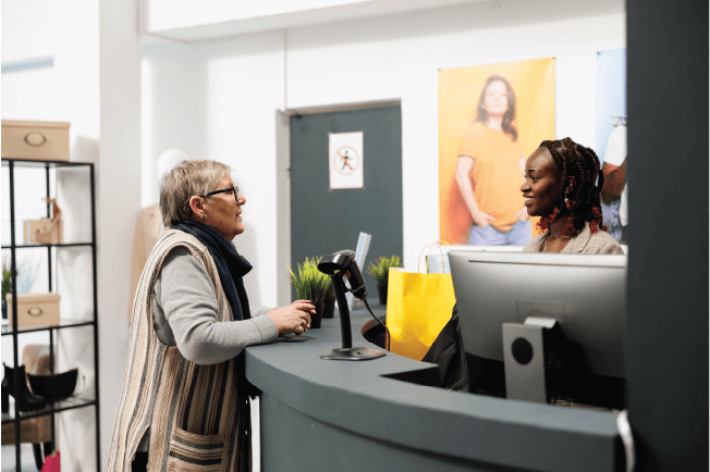 Customer talking to a retail cashier at a counter, highlighting risk management for running a safe church op shop.