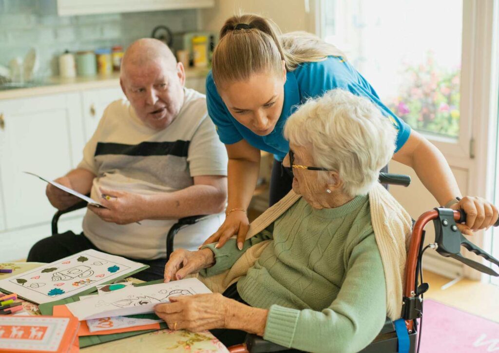 Care worker assisting senior residents with activities in a kitchen, representing specialized aged care insurance risks.