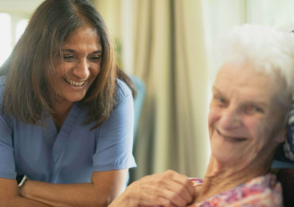 Care worker smiling alongside a happy elderly woman, highlighting tailored choices for aged care insurance.