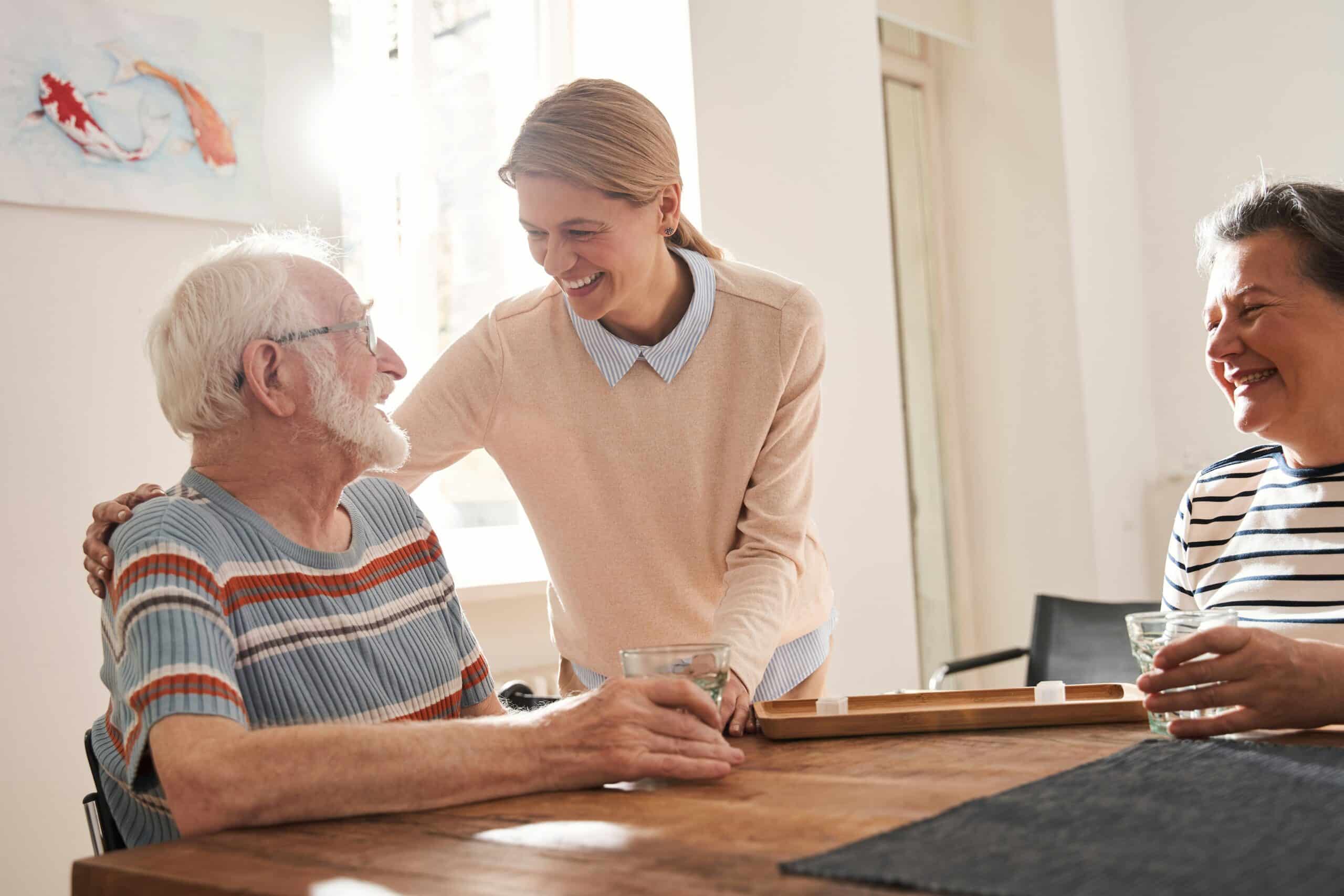 Care worker talking with elderly residents in a lounge, illustrating choices for aged care insurance.