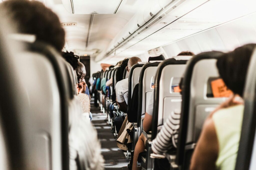 Passengers seated inside an airplane cabin, highlighting emergency medical cover and travel insurance considerations.