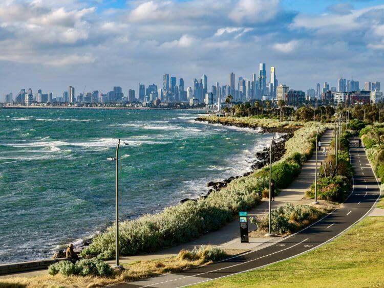 Scenic view of a coastal pathway overlooking a major city skyline, highlighting Melbourne aged care insurance.