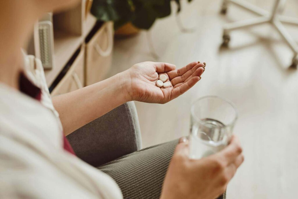 Care worker offering medication pills and a glass of water to a senior resident, detailing aged care provider risks.